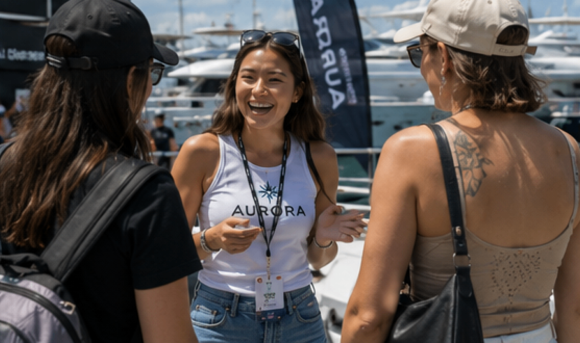 Brand ambassador in a white Aurora top speaking with guests on a sunny marina quay