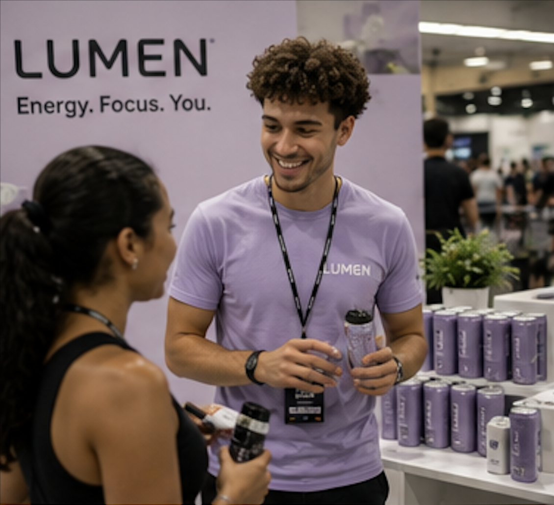 Male brand ambassador in a lilac branded T-shirt introducing products to a guest at a wellness expo stand