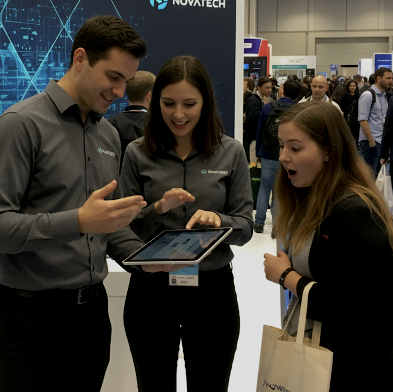 Exhibition staff demonstrating a tablet to a guest at a tech expo stand