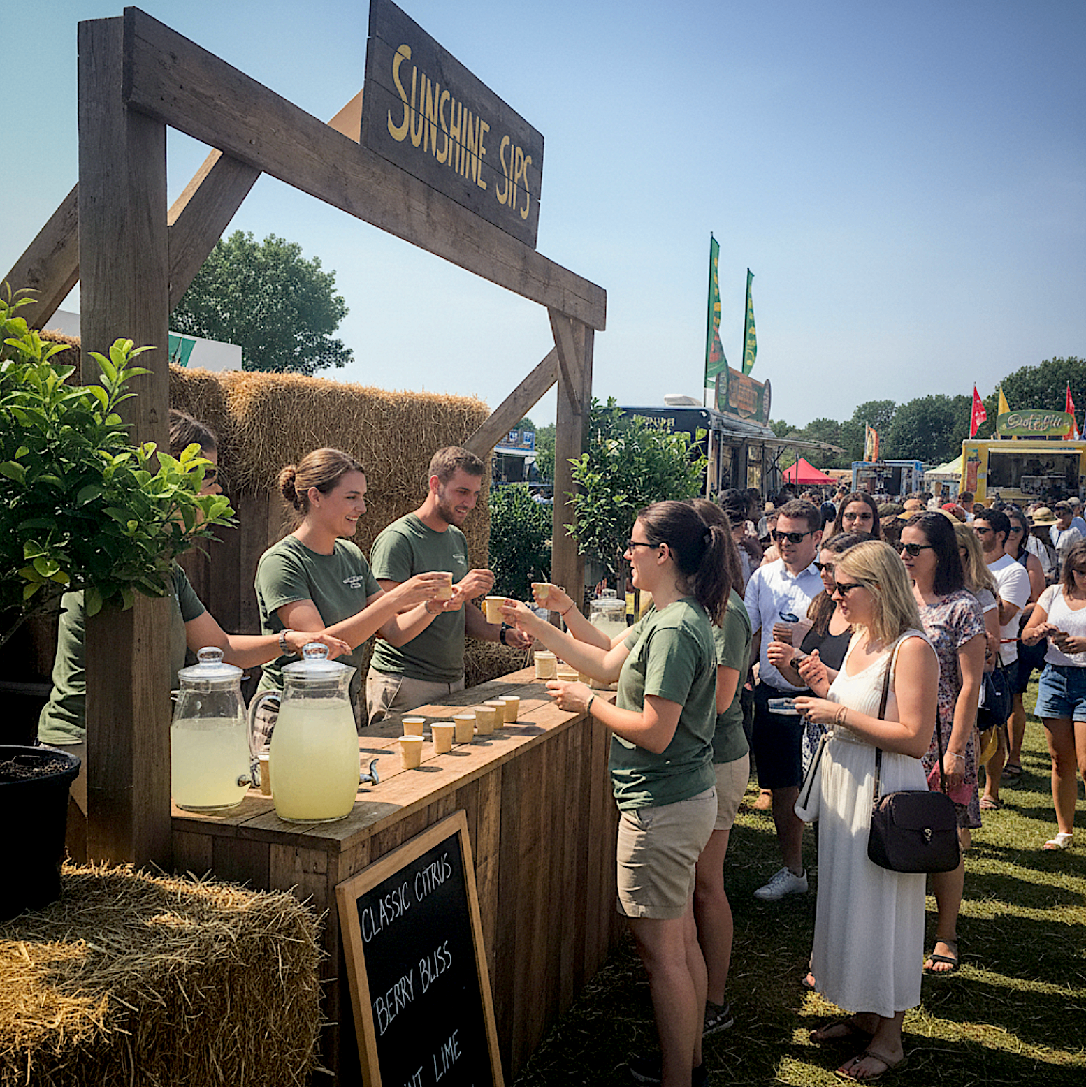Sampling staff serving cold drinks to guests from a branded outdoor activation bar